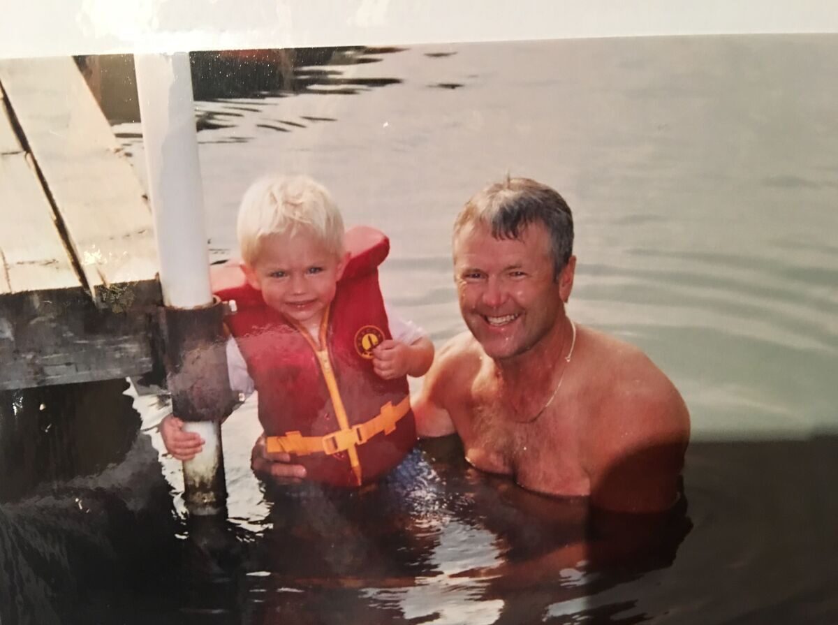 A younger Ken Nelson in the lake with a small child in a life jacket at the Shalom Park dock